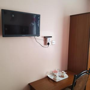 Monrovia Guest House في ناكورو: تلفزيون على جدار مع كوبين على طاولة