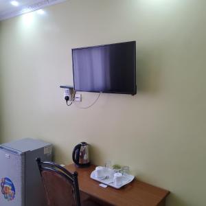 uma televisão sobre uma parede por cima de uma mesa de madeira com uma característica de escrita móvel em Monrovia Guest House em Nakuru