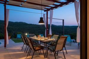 - une table et des chaises sur une terrasse avec vue dans l'établissement Villa LucaToni - luxury villa connected with nature - heated pool, à Šibenik
