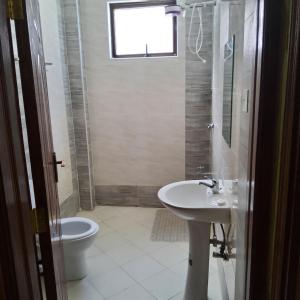 a bathroom with a sink and a toilet and a window at Monrovia Guest House in Nakuru