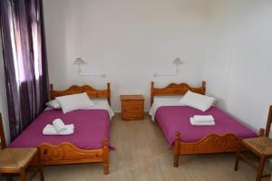 two beds in a room with purple sheets at PERDIKI STUDIOS in Kókkinon Nerón