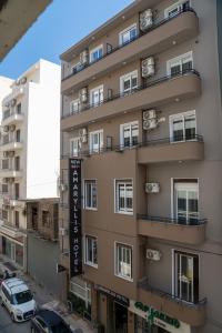 un edificio alto con coches estacionados frente a él en New Amaryllis Hotel en Atenas