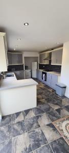 uma grande cozinha com armários brancos e piso em azulejo em Well presented 3 Bed House- 9 Guests - Great for Leisure stays or Contractors -NG8 postcode em Nottingham