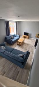 Well presented 3 Bed House- 9 Guests - Great for Leisure stays or Contractors -NG8 postcode في نوتينغهام: غرفة معيشة مع كنبتين زرقاوين وطاولة