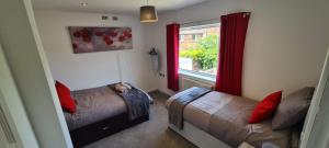 a bedroom with two beds and a window with red curtains at 3 Bed House NG8- Great for Leisure stays or Contractors in the area Close to M1 in Nottingham