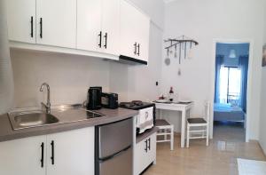 a kitchen with white cabinets and a sink at Makis Apartments in Arillas