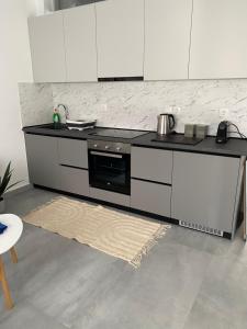 a kitchen with a stove and white cabinets and a rug at Olympia's Guest House in Volos