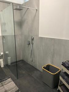 La salle de bains est pourvue d'une douche avec une porte en verre et d'un seau. dans l'établissement Olympia's Guest House, à Vólos