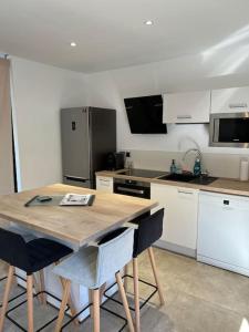 een keuken met een houten tafel en een aantal stoelen bij Studio indépendant avec accès piscine in Uzès