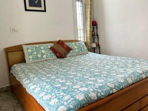 a bed with a blue comforter and two pillows on it at Cozy Nest - Garden Facing Apartment with Kitchen in Chandīgarh