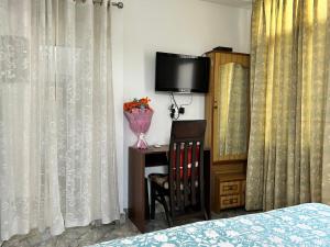 a bedroom with a bed and a tv and curtains at Cozy Nest - Garden Facing Apartment with Kitchen in Chandīgarh