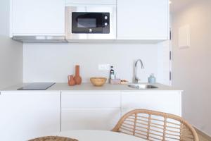 a white kitchen with a microwave and a sink at Banana Beach Boutique Studio in Platja  d'Aro