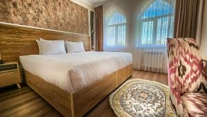 a bedroom with a large bed and a chair at Hotel Bankir Khiva in Khiva