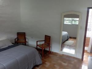 a bedroom with a bed and two chairs and a mirror at San Cayetano in San Salvador de Jujuy