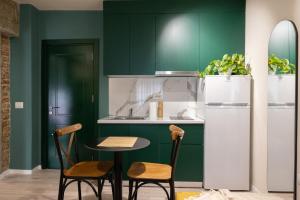 una cucina con armadi verdi, tavolo e sedie di Three doors apartments, Kiwi 1+1 apartment a Tirana