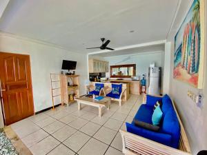 a living room with blue couches and a kitchen at Lembongan Sanctuary Villas in Nusa Lembongan
