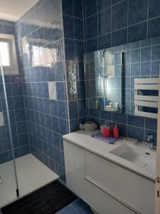 a blue tiled bathroom with a sink and a mirror at Maison ensoleillée et reposante in Le Château-dʼOléron