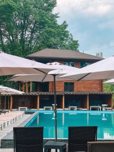 a pool with umbrellas and chairs and a building at Kolyba Club in Stanishovka