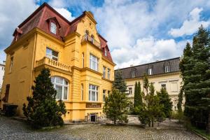 a large yellow building with a red roof at Aphrodite Hotel Marianske Lazne in Mariánské Lázně