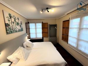 um quarto com uma cama branca e 2 janelas em La Casita Villa Vacacional em Anero