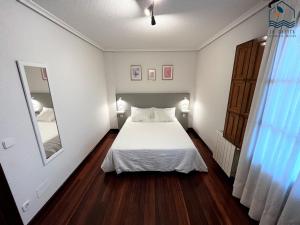 um quarto com uma cama branca e um espelho em La Casita Villa Vacacional em Anero