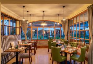 a restaurant with tables and chairs and windows at Fairmont Mount Kenya Safari Club in Nanyuki