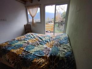 1 cama con un edredón colorido en un dormitorio con ventana en Vista los Andes en Cacheuta