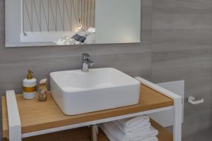 W łazience znajduje się biała umywalka i lustro. w obiekcie Hermagio Villa George by Estia w mieście Malia