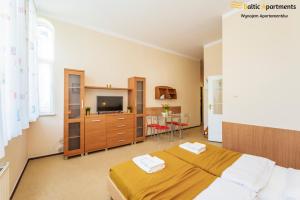 ein Schlafzimmer mit einem Bett und einem TV in der Unterkunft Baltic Apartments - Willa Carmen in Świnoujście