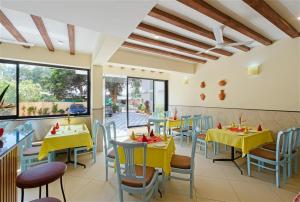 a restaurant with yellow tables and chairs and a large window at Aastha Escape Resort near Calangute Beach in Calangute