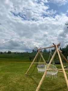 a swing set in a field with a cloudy sky at Bungalovi Mijakovici in Pljevlja