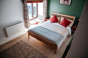 Un dormitorio con una cama con almohadas rojas y una ventana en The Old Stable at Blackshaw Farm en Leek