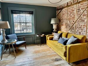 a living room with a yellow couch and a brick wall at Fabulous apartment seconds from beach by Whitstable-Holidays, Pudding Pan in Whitstable