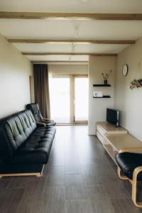 un soggiorno con divano e TV di Durbes Atvari - brīvdienu mājas ar saunu a Durbe