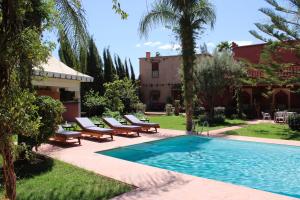 El Jemʼa Ghemat的住宿－Villa DALIA Route Ourika en Exclusivité，一座房子旁带躺椅的游泳池