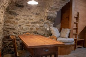 a dining room with a table and a stone wall at Busc De Crodol in Comune Rivamonte Agordino