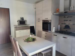 een keuken met een witte tafel met stoelen en een magnetron bij Casa Dany in Albissola Marina