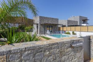 uma parede de pedra em frente a uma casa com piscina em Hermagio Villa George by Estia em Malia