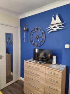 a blue wall with a clock and a wooden dresser at The Hut Wales - A Sea Front Inn in Holyhead