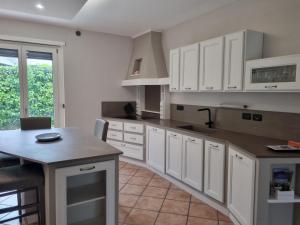 uma grande cozinha com armários brancos e uma mesa em Suite vacanze Chabloz nel cuore della Valle d'Aosta em Nus
