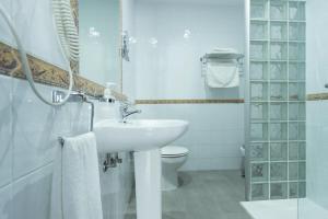 a white bathroom with a sink and a toilet at Hostal El Yunque in Conil de la Frontera