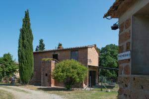 ein altes Backsteingebäude mit einem Baum davor in der Unterkunft ROSMARINO in Città della Pieve