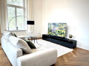 uma sala de estar branca com um sofá e uma televisão em Palais Passy~Design Suite mit Ausblick im Zentrum em Wiesbaden