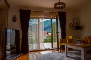 a living room with a tv and a large window at The View Apartment in Visoko