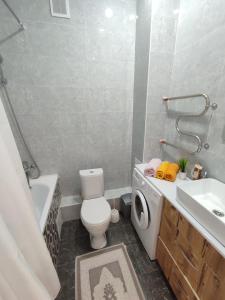 a bathroom with a toilet and a sink and a washing machine at Уютная квартира в центре левого берега in Taldykolʼ