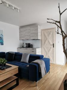 a living room with a blue couch and a kitchen at Apartamenty PRZYSTAŃ Chłopy in Chłopy