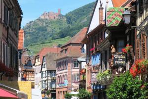 a city street with buildings and a castle in the background at Victor et Léontine in Ribeauvillé