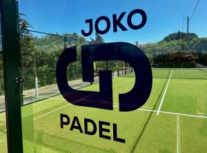 Un cartel en una cancha de tenis frente al cartel de AJ Salsaoked. en Hotel La Romarine, en Saint-Tropez
