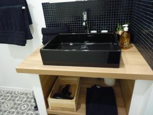 un bagno con lavandino nero su un bancone di Gite Les Matines a Sebourg