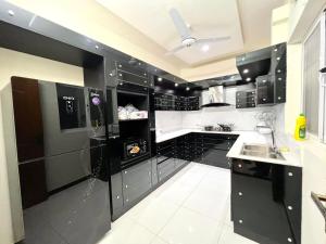 una cocina en blanco y negro con electrodomésticos negros en LUXURY 6 Bedroom Holiday Home en Islamabad
